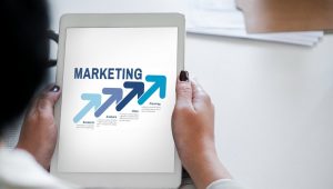 Pessoa segurando tablet com conceito de marketing e setas de crescimento representando estratégia e planejamento