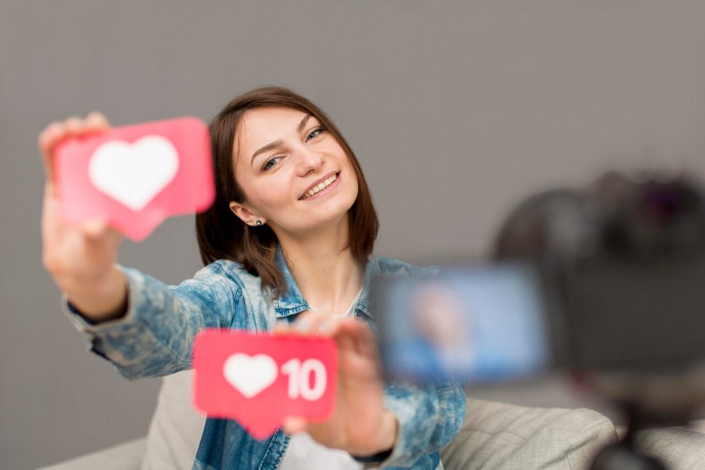 Criadora de conteúdo segurando ícones de curtidas e engajamento em ação de marketing digital e redes sociais