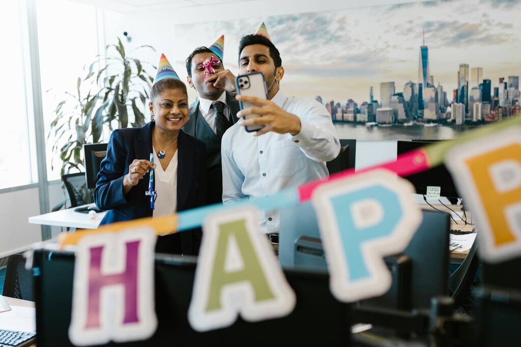 Funcionários tirando foto durante a decoração festiva do escritório em comemoração ao aniversário de empresa.