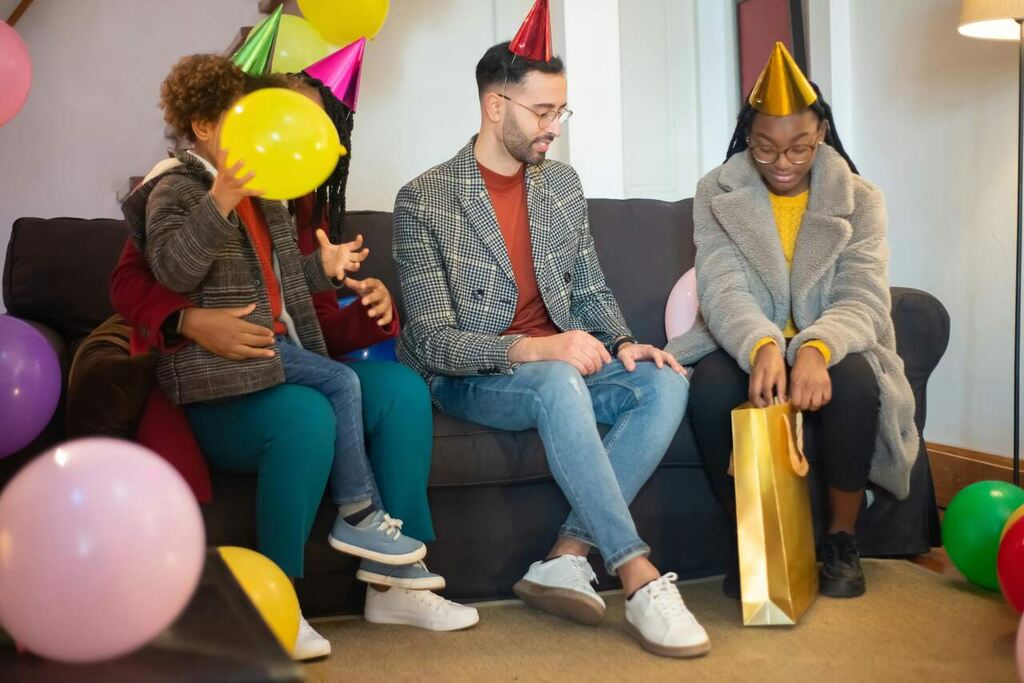 Pessoas comemorando com balões e presentes em clima festivo, ideal para ilustrar aniversário de empresa com colaboradores.
