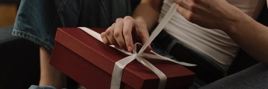pessoa abrindo caixa de presente com um dos tipos de lembrancinhas personalizadas
