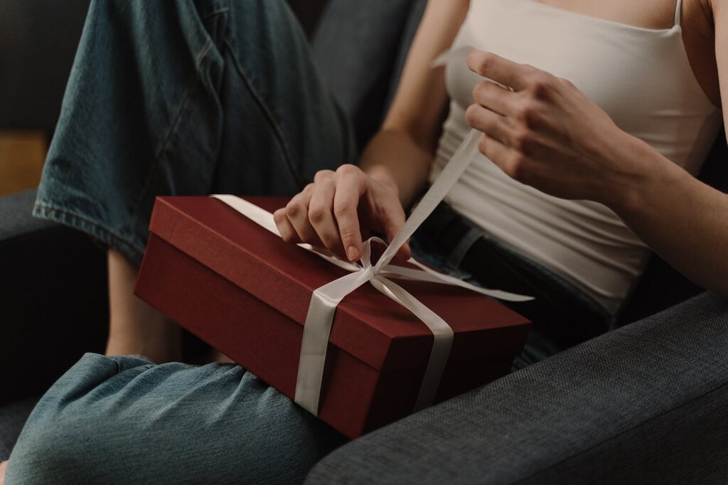 pessoa abrindo caixa de presente com um dos tipos de lembrancinhas personalizadas