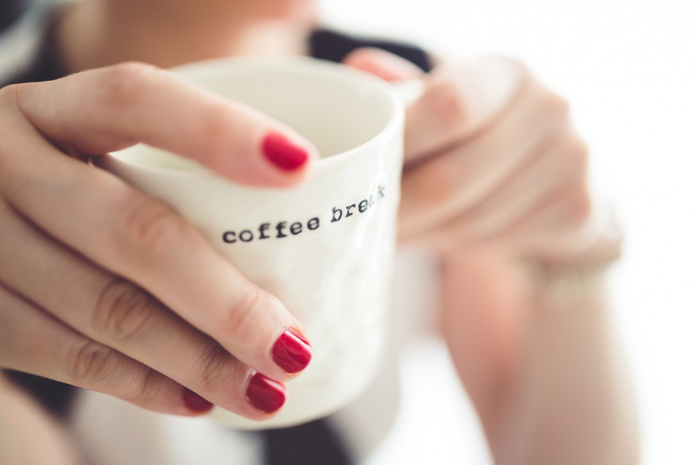 Close em mãos segurando xícara com texto discreto, exemplo de aplicação minimalista de frases para xícaras de café no dia a dia.