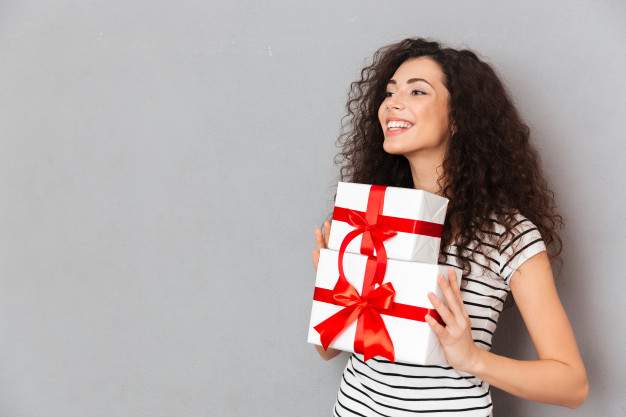 half turned photo gorgeous female striped t shirt holding two gift wrapped boxes with red bows being excited joyous grey wall 171337 221